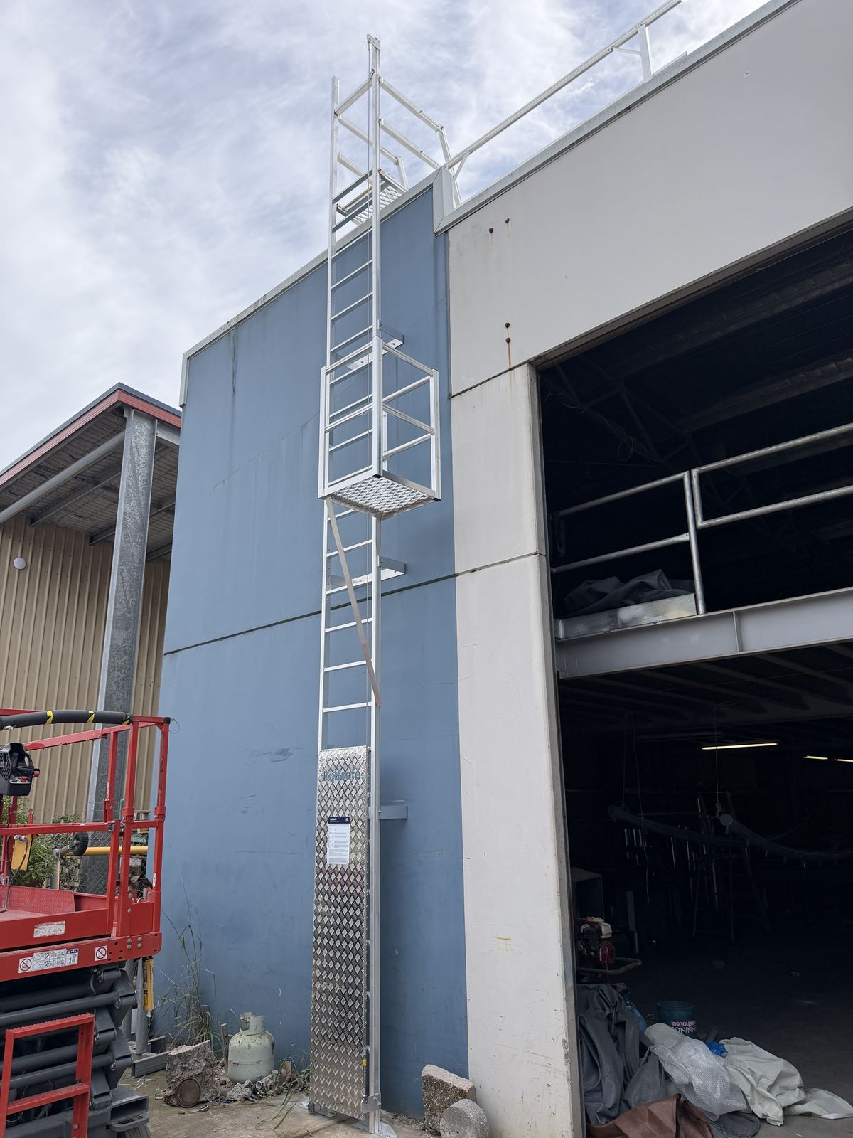Vertical static line ladder mounted on external building wall